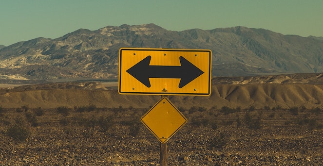 Yellow caution arrows pointing in opposite directions with mountains in background