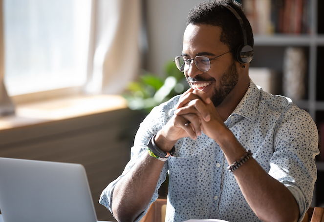 Man looking at computer smiling with hands folded