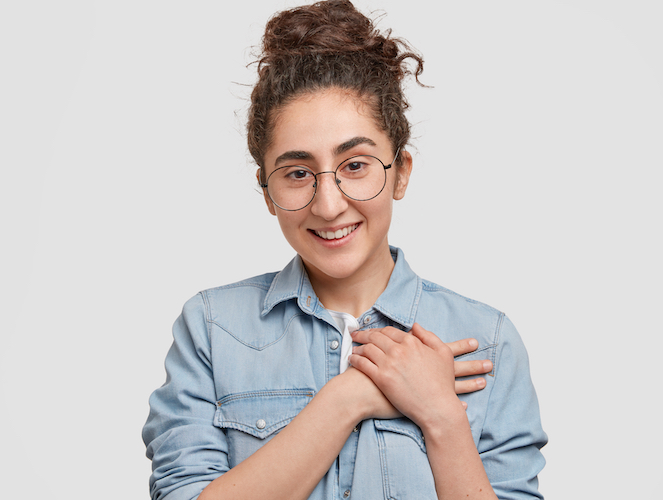 Young women smiling and holding hands over her heart